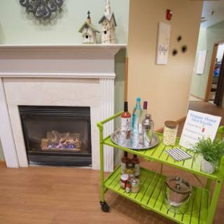 A cozy living space featuring a modern fireplace and a vibrant green cart adorned with decorative items.