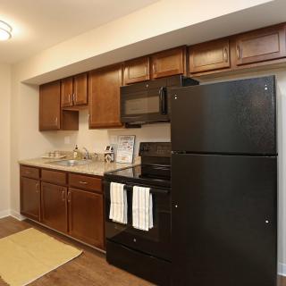 A cozy kitchen with wooden cabinets and black appliances.