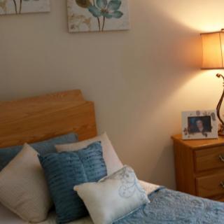 A cozy bedroom with a wooden bed, decorative pillows, and a bedside lamp.