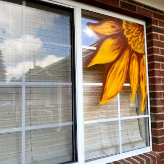 A beautifully painted sunflower accentuating the window of a home.
