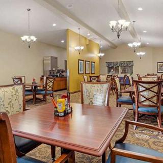A spacious dining area with wooden tables and chairs, adorned with elegant chandeliers.