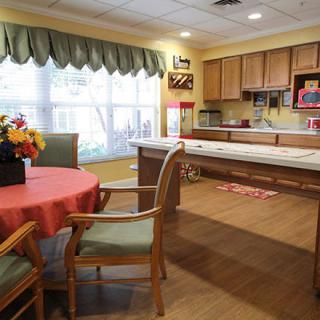 A cozy kitchen and dining area featuring a round table with chairs, cabinetry, and large windows with curtains.