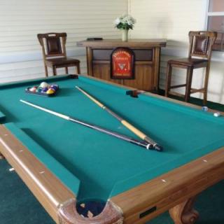 A billiard table setup with cues and balls in a recreational area.