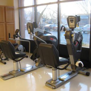 A pair of recumbent exercise bikes positioned near a large window in a fitness setting.