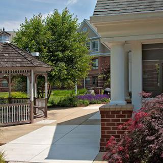 A serene garden view featuring a gazebo, pathway, and vibrant greenery in a residential area.