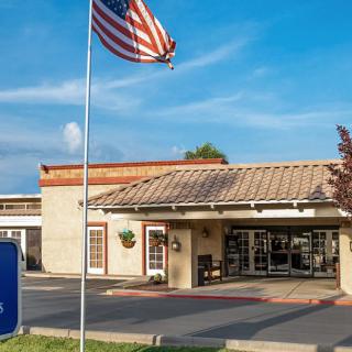 A hotel entrance with an American flag and clear signage.