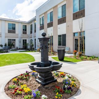 A beautiful courtyard featuring a central fountain surrounded by colorful flowers and modern architecture.