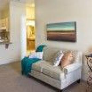 A cozy living room with a comfortable sofa and a landscape painting on the wall.