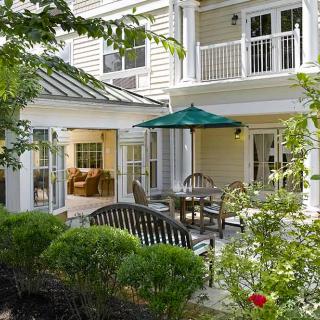 A tranquil garden patio with outdoor seating and an umbrella, set against the backdrop of a charming house.