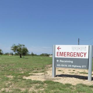Emergency sign directing to a healthcare facility on a clear day.