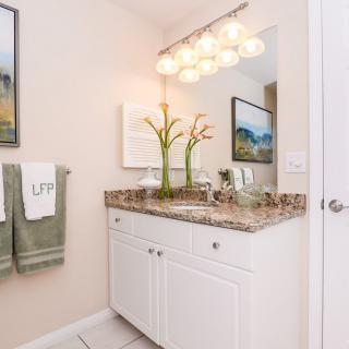 A modern bathroom with a granite countertop, neatly arranged towels, and decorative plants.