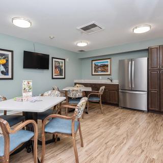 A modern dining and kitchen area with tables, chairs, a TV, and stainless steel appliances.