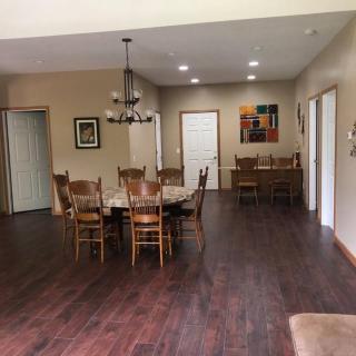 A spacious dining room with a wooden table and chairs, elegant chandelier, and artwork on the wall.