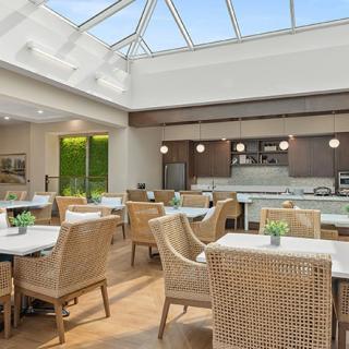 A modern dining area with natural lighting, featuring wicker chairs and a skylight.