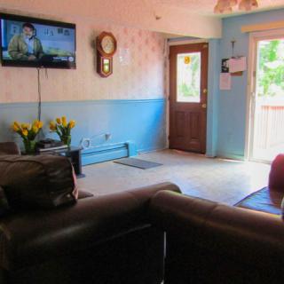 A cozy living room with a sofa, wall-mounted television, and door leading outside.