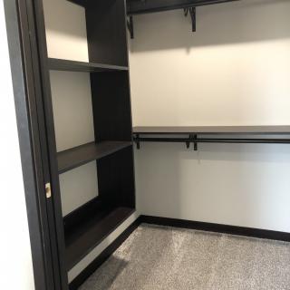 An empty walk-in closet with built-in shelving and hanging rods.