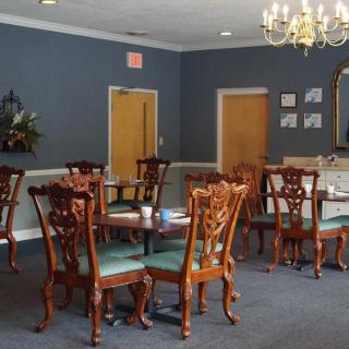 A well-furnished dining room with elegant wooden chairs and tables under a chandelier.