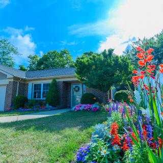 A charming home surrounded by vibrant flowers under a bright blue sky.