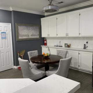 A modern kitchen with a dining area featuring a round table surrounded by comfortable chairs, white cabinets, and a decorative painting.