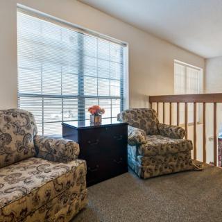 A cozy living space featuring two patterned armchairs near large windows with ample natural light.