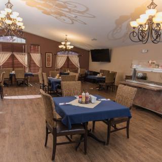A cozy dining room with neatly arranged tables and elegant chandeliers.