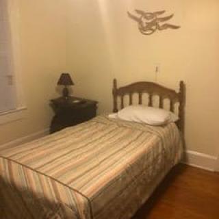A cozy bedroom with a single bed, nightstand and wall decor.