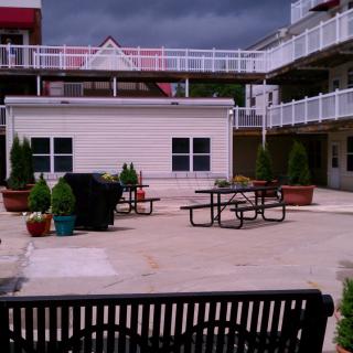 A courtyard with a bench, picnic tables, and potted plants surrounded by buildings.