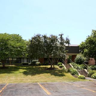 A building surrounded by trees with a parking lot in the foreground.