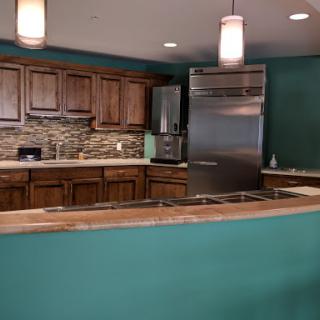 A modern kitchen featuring wood cabinetry, stainless steel appliances, and a vibrant green accent wall.