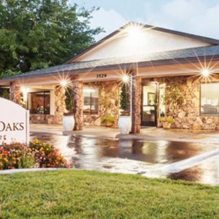 A well-lit building exterior with a sign reading 'Oaks' and wet pavement reflecting the lights.