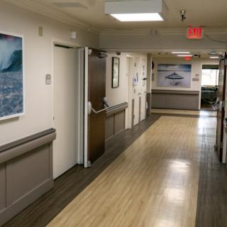 A quiet hospital hallway with doors on either side and bright overhead lighting.