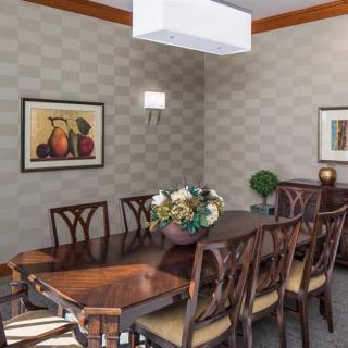 A stylish dining room featuring a long wooden table with matching chairs, elegant wall decor, and ambient lighting.