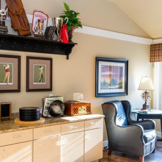 A cozy home office with decorative shelves, elegant artwork, and a comfortable leather chair.