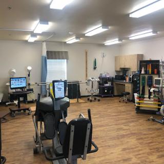 A well-equipped rehabilitation therapy room with various exercise machines and therapeutic devices.