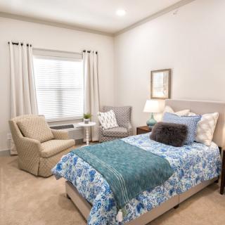 A cozy bedroom with a single bed, armchair, and elegant decor.