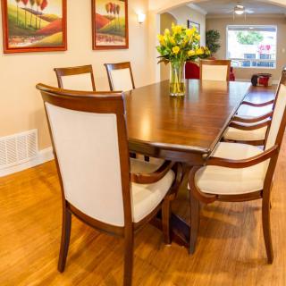 A well-furnished dining room with a wooden table, chairs, artwork on the walls, and a vase of flowers.