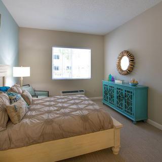 A cozy bedroom with a large bed, turquoise dresser, and decorative mirror.