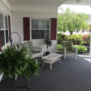 A cozy outdoor porch with a swing, chairs, and lush plants.