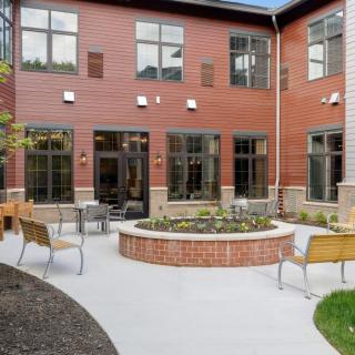 A charming courtyard with benches and chairs surrounded by a brick building.