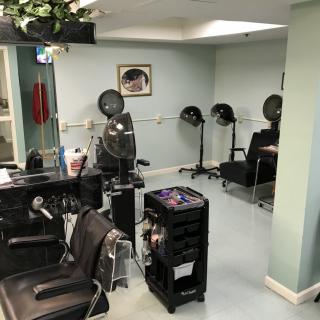 A cozy hair salon featuring styling chairs, hair dryers, and beauty equipment.