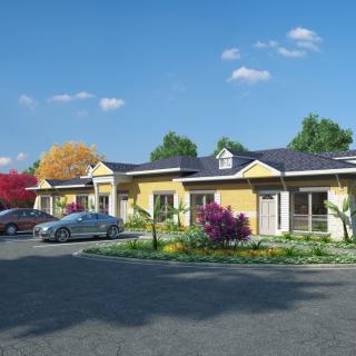 A suburban residential area with parked cars and a landscaped garden under a blue sky.
