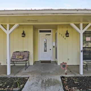 Front entrance of a yellow house with a porch and bench.