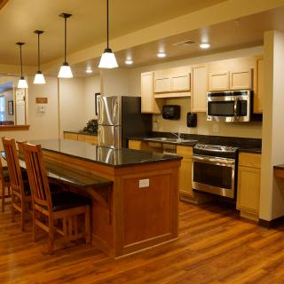 A modern kitchen with wooden floors, a spacious island, and stainless steel appliances.