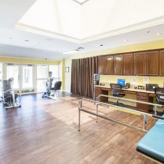 A spacious therapy room designed for rehabilitation, featuring exercise equipment and ample natural light.