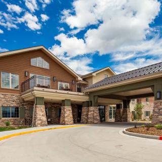 A modern residential building with stone accents and a covered driveway under a cloudy sky.