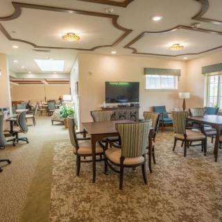 A spacious and elegantly designed dining area with tables, chairs, and a television.