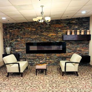 A cozy seating area with two armchairs facing a modern fireplace set against a stone wall.