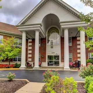A grand entrance of a two-story building featuring large columns and well-maintained landscaping.