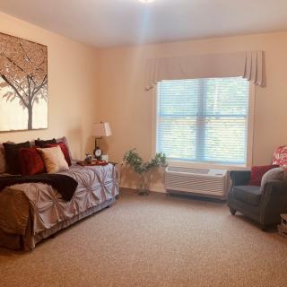 A cozy living area with a bed, armchair, and window allowing natural light.