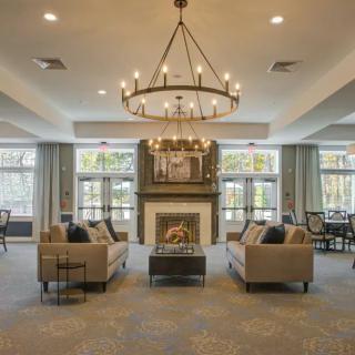 A spacious living room with elegant chandeliers, a central fireplace, and comfortable sofas.